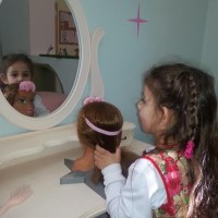 ילדה מסרקת בבובה בסלון היופי
